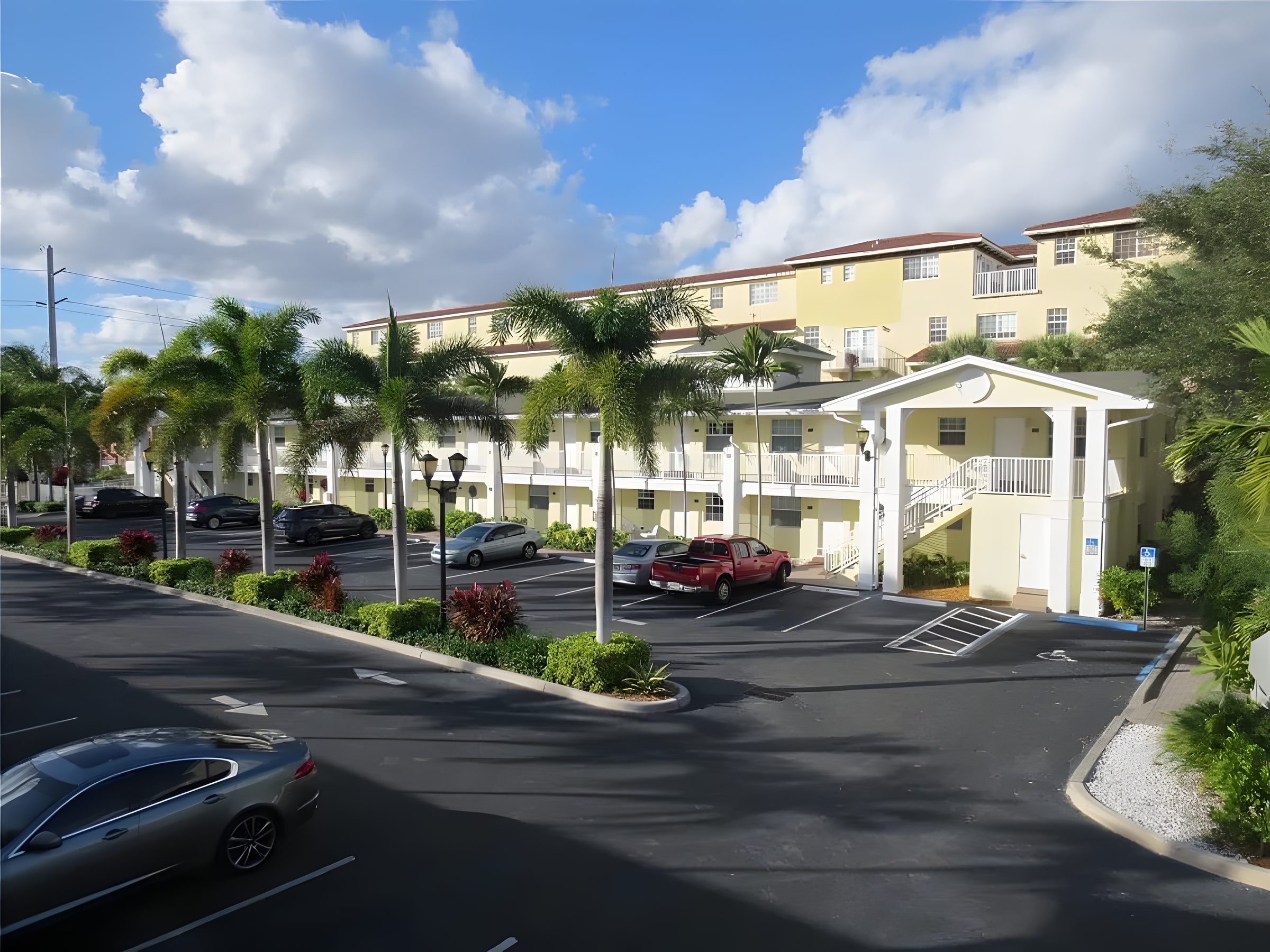 The Grove from the parking court, palms along the edge and the buildings beyond.